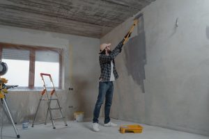 Image of a painter painting concrete wall. So, What Is Concrete Painting?